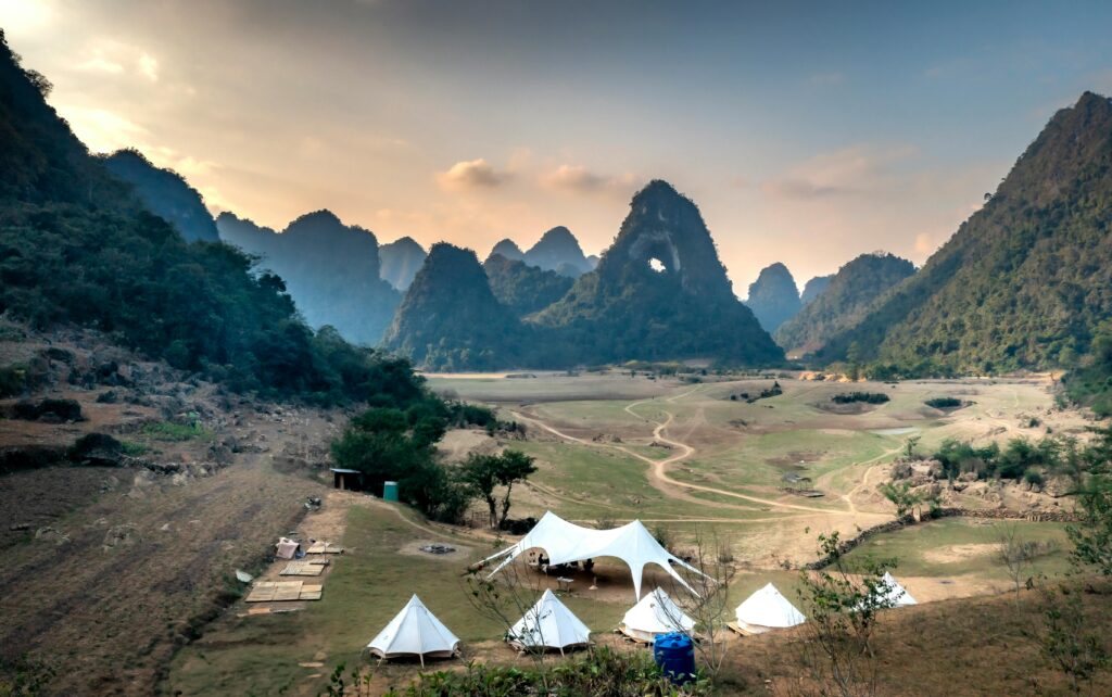 Idyllic camping scene with tents in a mountainous landscape at sunset.