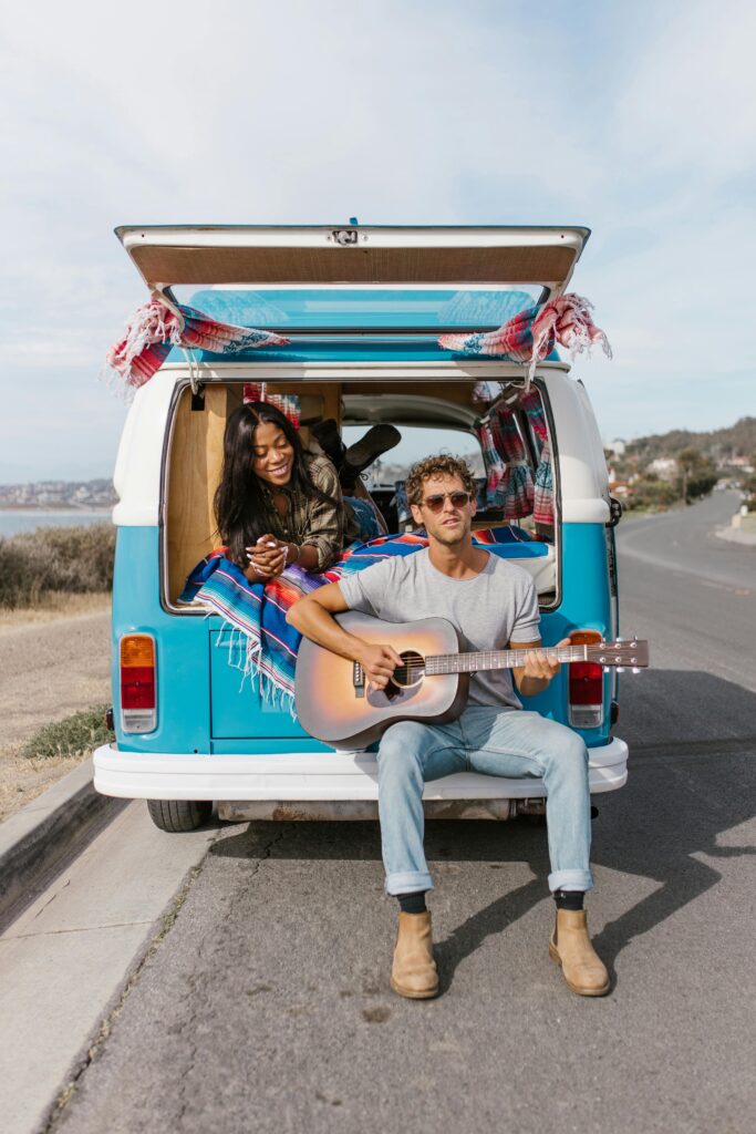 Young couple on a road trip in a campervan, enjoying music and scenery.